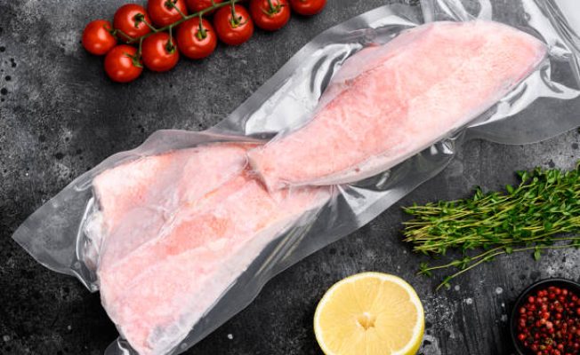 Red Snapper frozen pack fish meat set, with herbs, on black dark stone table background, top view flat lay